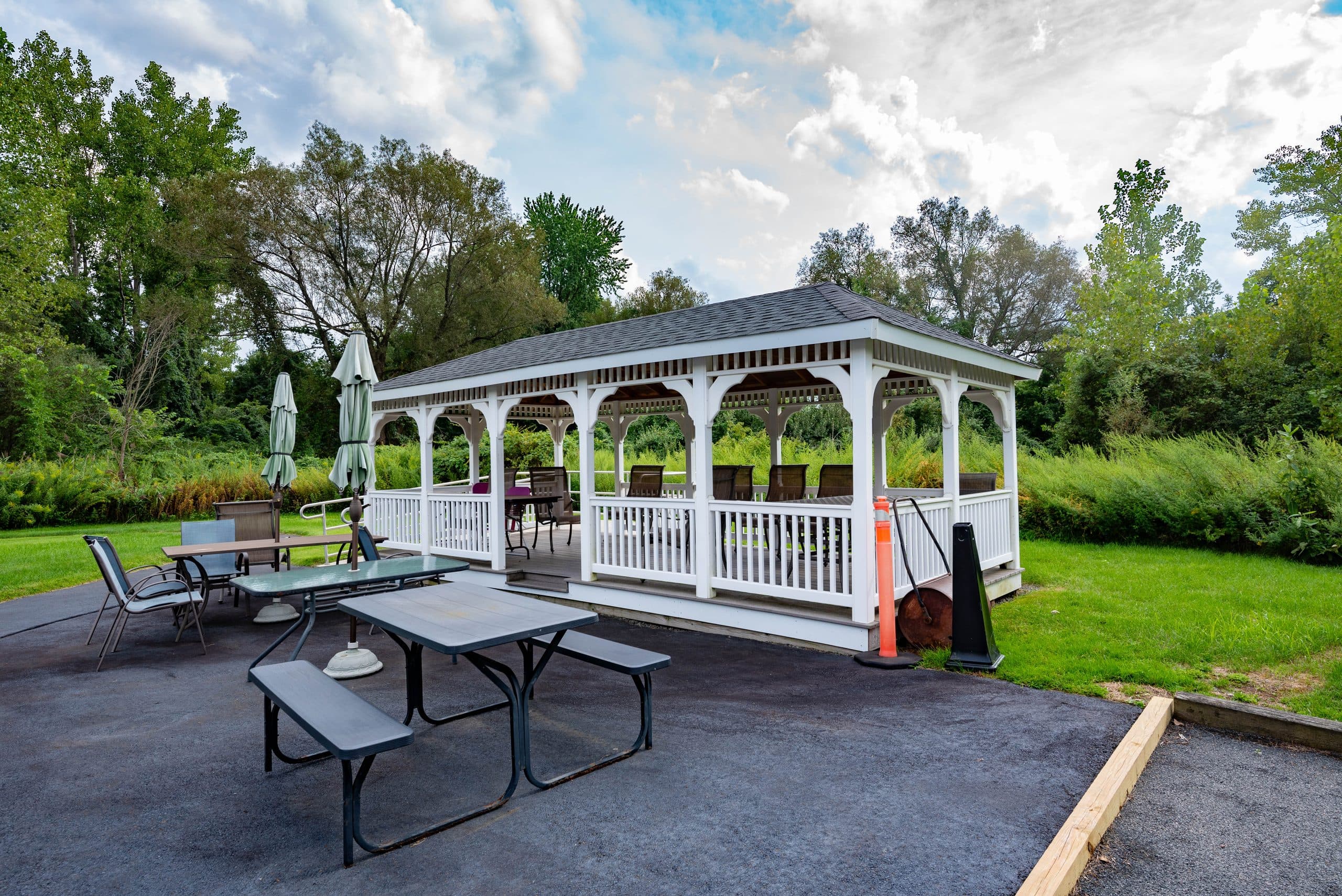 The covered pavilion and patio, with picnic tables and umbrellas on the lawn among the trees